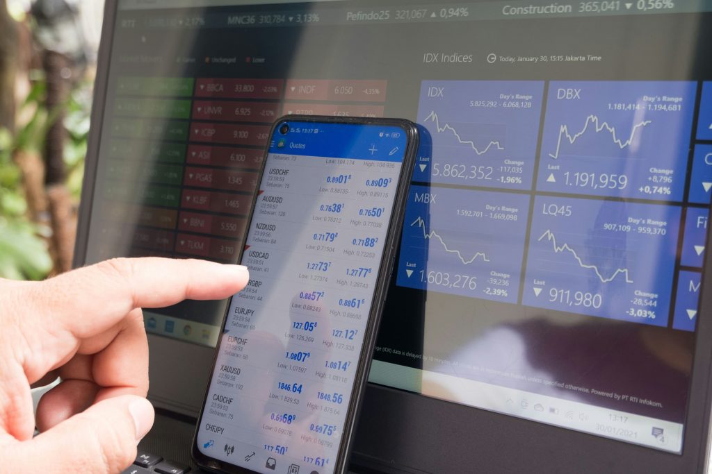 Mobile trading quotes in front of financial market screens