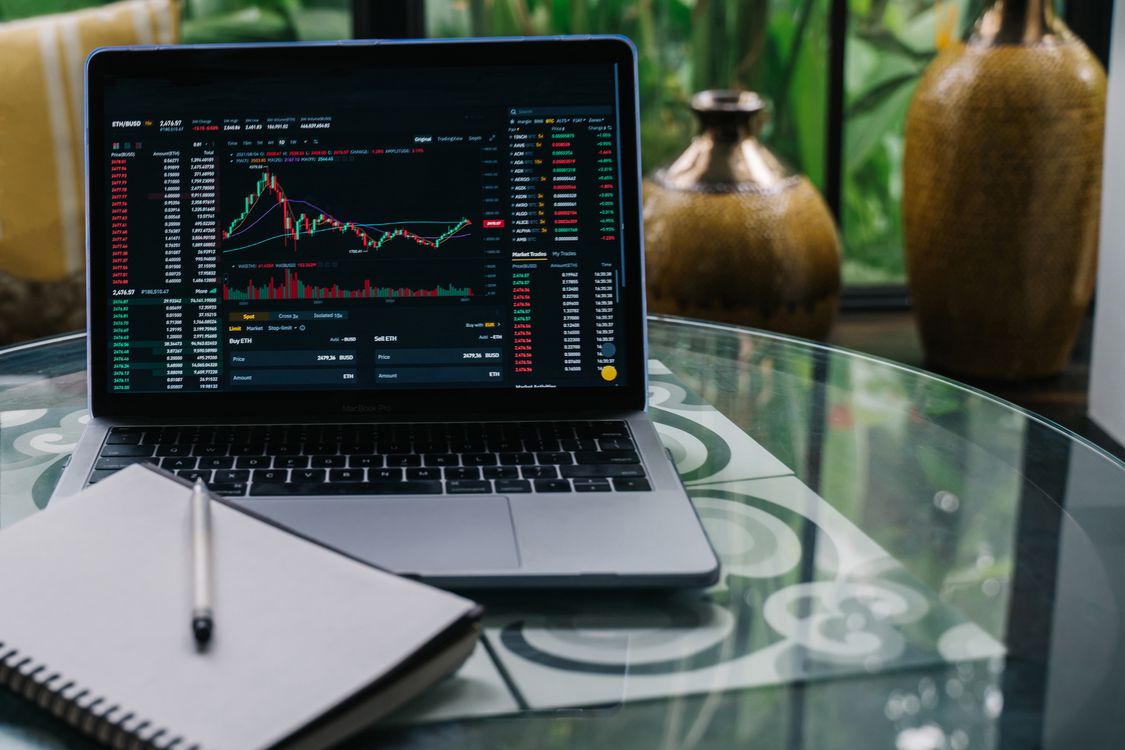 Laptop displaying cryptocurrency trading charts on a desk