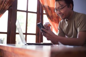 Person making an online payment with smartphone, credit card and laptop for NetNapz stablecoin payments coverage